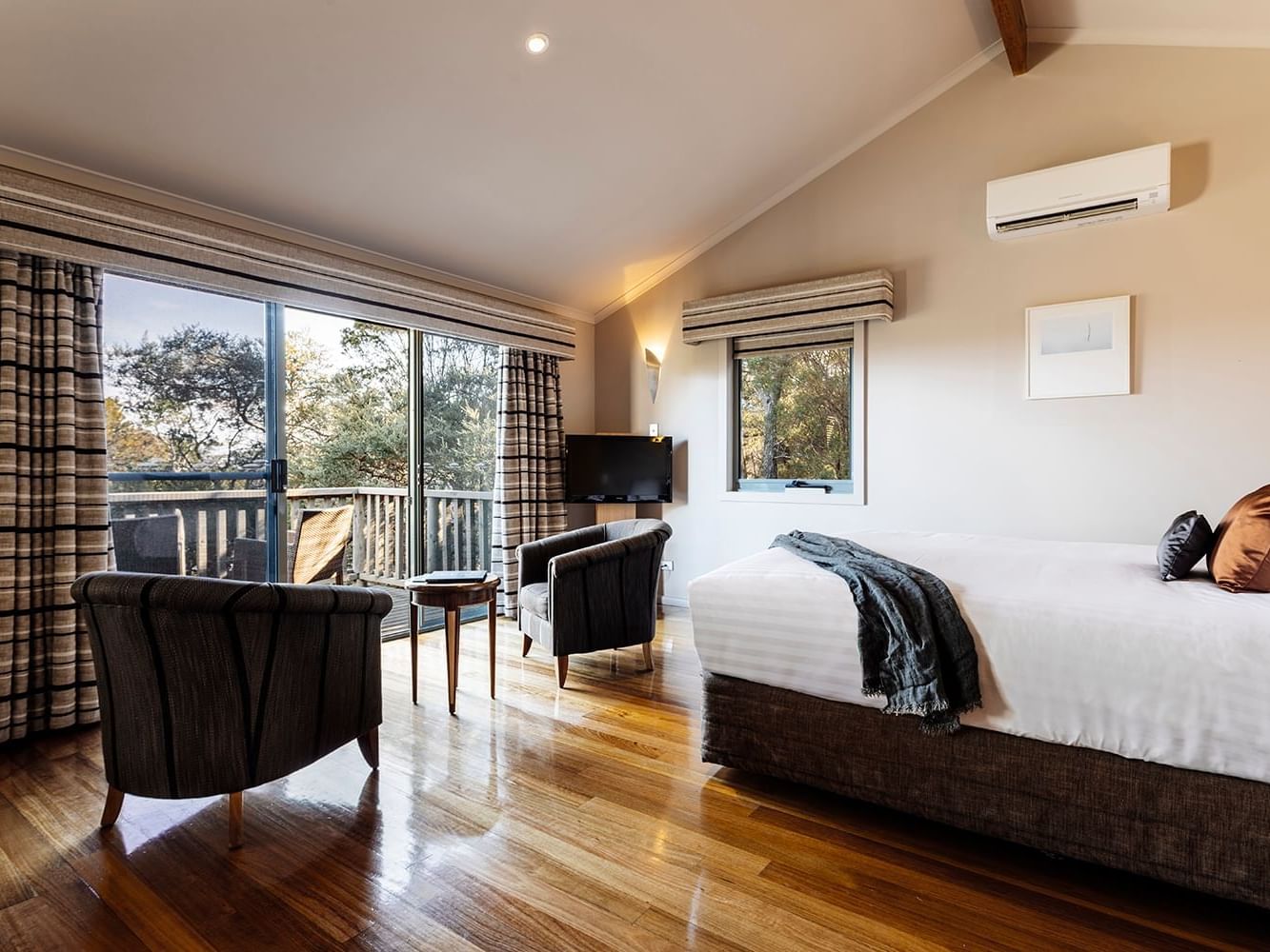 Seating area by bed in Premier Spa Cabin with wooden floors at Freycinet Lodge