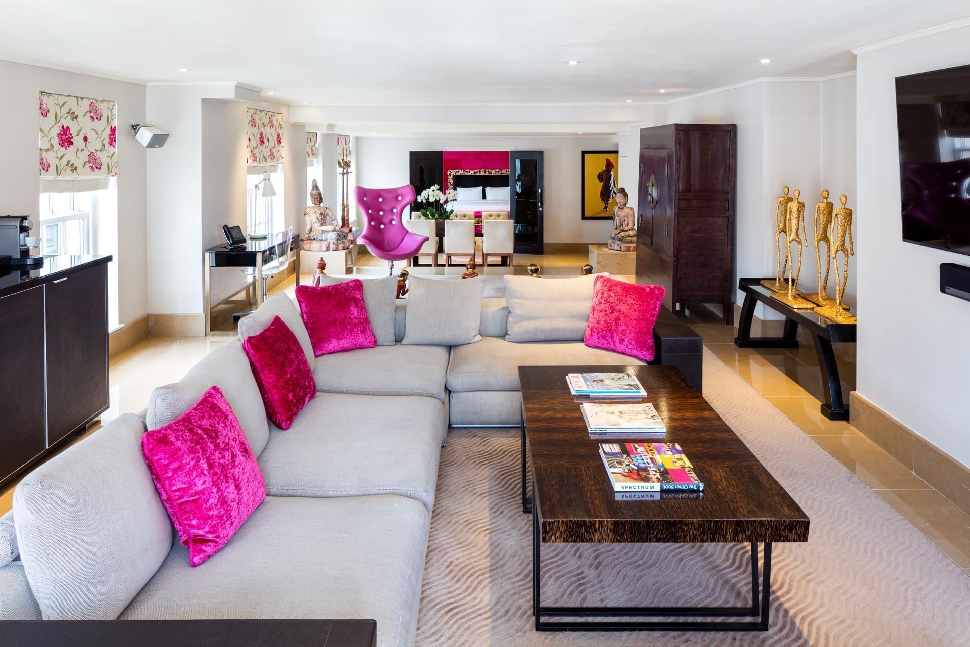 Schiaparelli Suite lounge with a large sectional with pink pillows at The May Fair Hotel