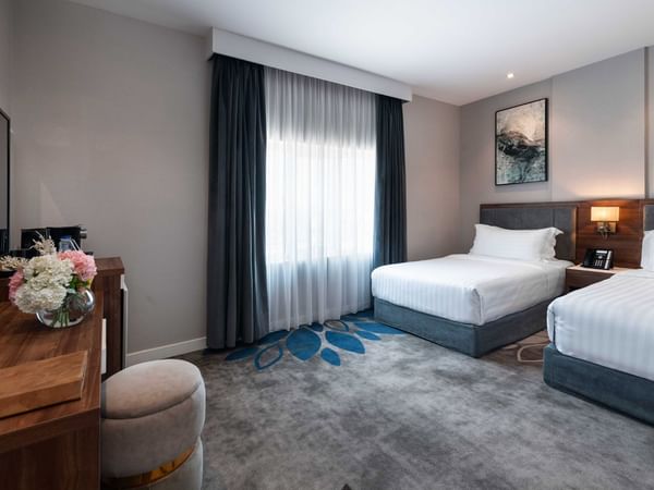 Spacious room with two beds and a work area at Warwick Hotel Al Jubail