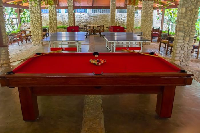 Red billiards table and ping pong tables under a canopy with stone pillars at Hotel Chan-kah Resort Village