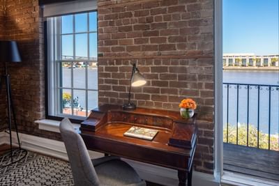 Work desk with table lamp & a chair in River View Two Room Suite with King Bed at River Street Inn