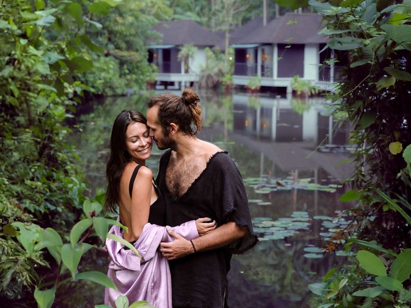 Couple embracing in lush greenery by a lotus pond under the CELEBRATE VALENTINE'S STAY offer for water villa