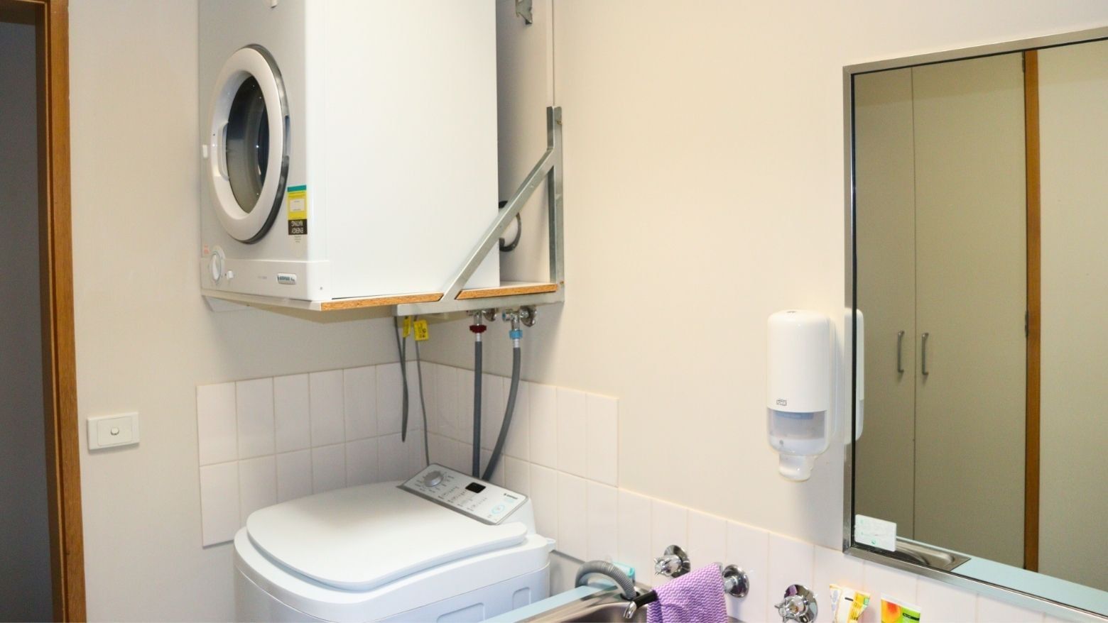 White washing machine and dryer combo in a compact laundry room.