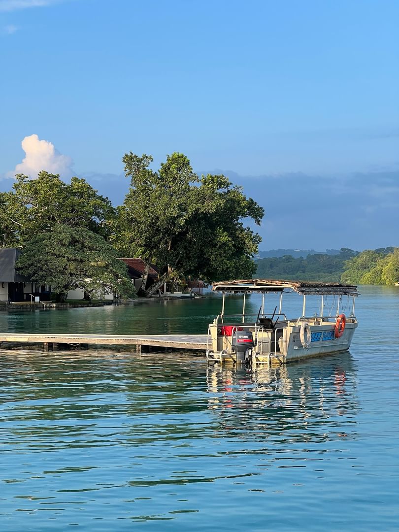 Small motorboat by a wooden pier under a blue sky surrounding tropical trees near Warwick Le Lagon Efate