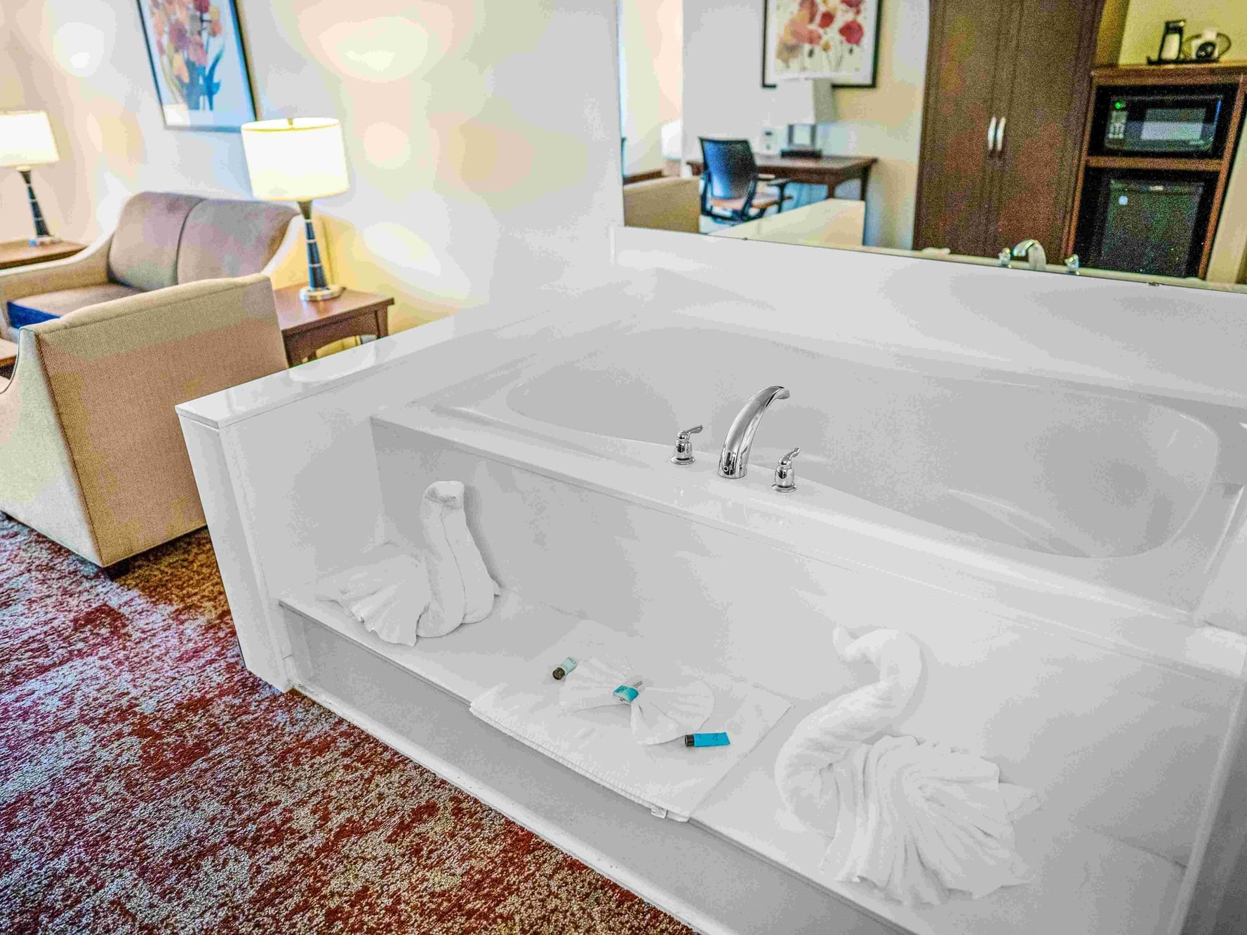 White jetted tub with towel swans in suite with seating area at Crystal Inn Salt Lake City