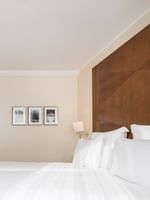 Twin beds by a wooden console with a TV under framed art near the room entrance in Classic Room at Warwick Geneva