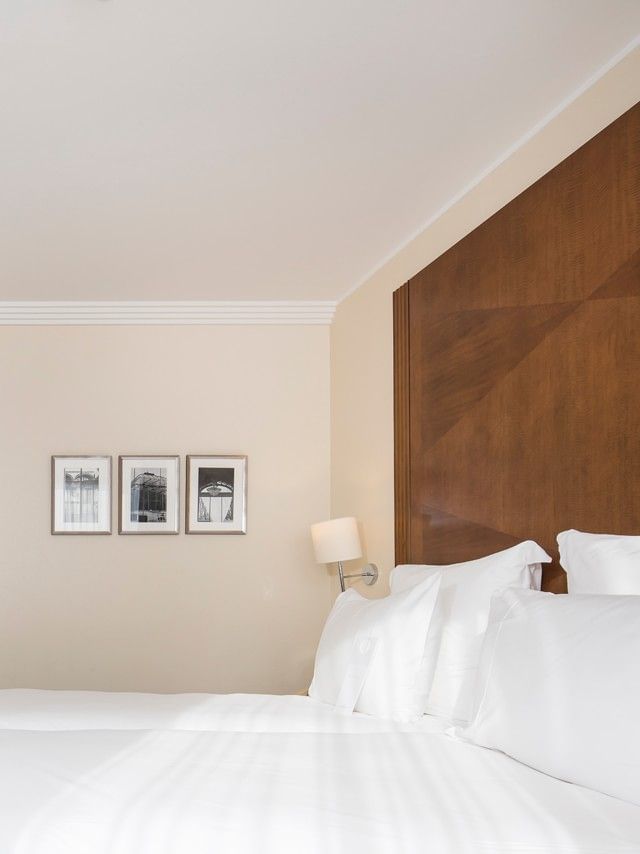 Twin beds by a wooden console with a TV under framed art near the room entrance in Classic Room at Warwick Geneva
