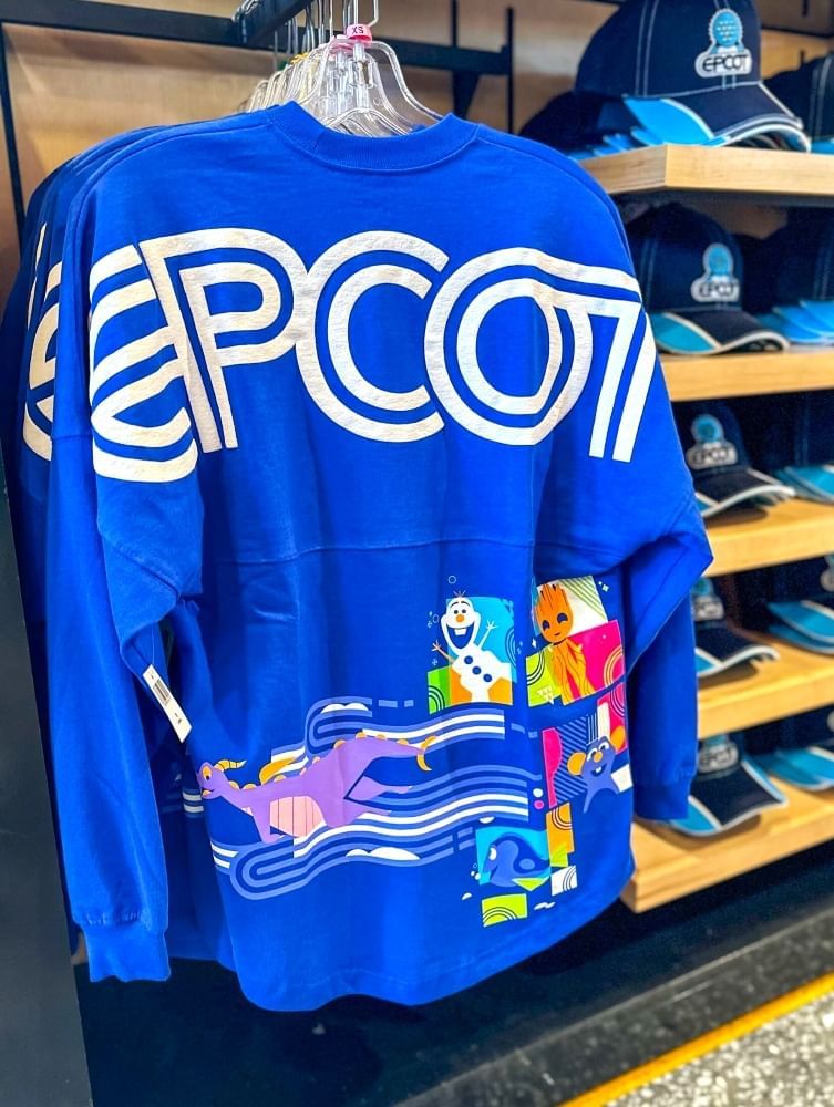 A bright blue spirit jersey hanging on a rack with EPCOT in white letters and a colorful graphic design below.