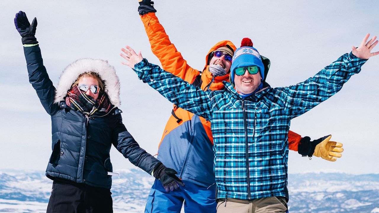 three people standing on top of a mountain