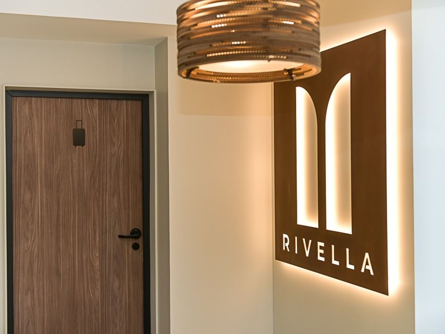 Porte en bois et panneau lumineux Rivella éclairé à l'intérieur d'un hôtel