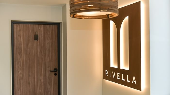Porte en bois et panneau lumineux Rivella éclairé à l'intérieur d'un hôtel