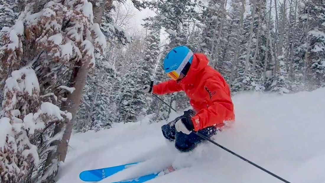 Man skiing on a snow path surrounded by snowy trees near Chateaux Deer Valley