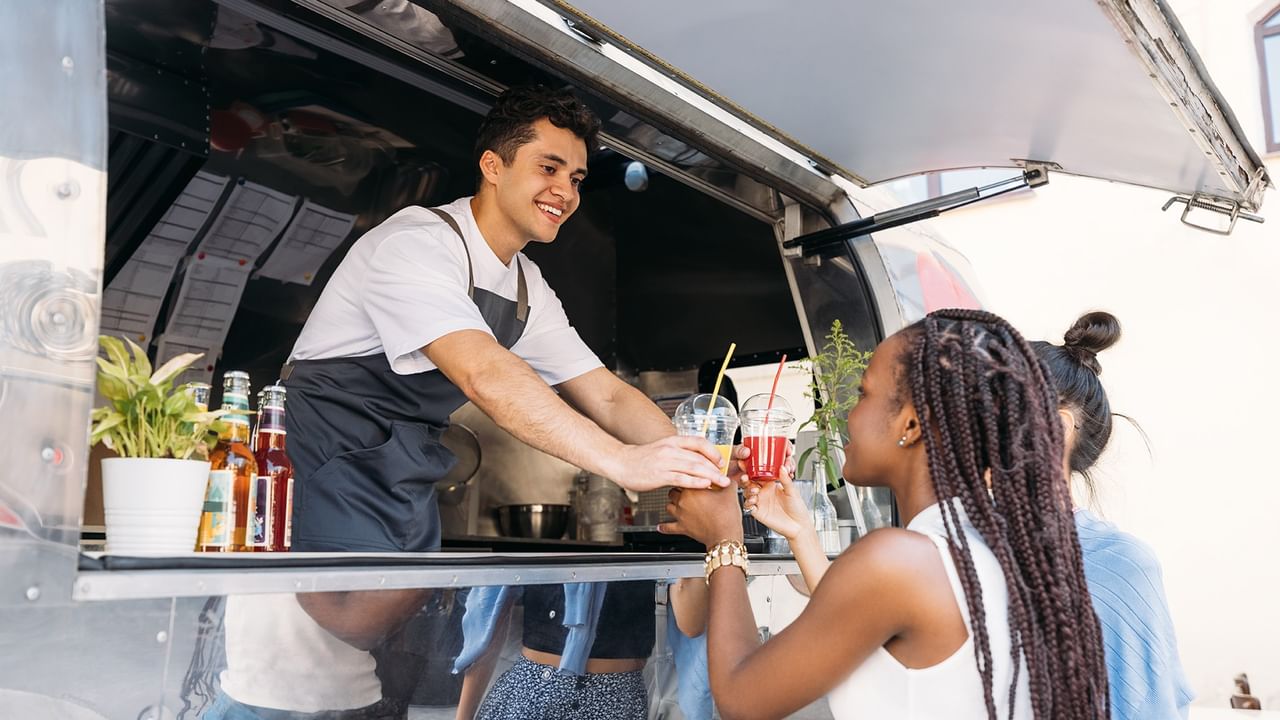 a food truck server handing drinks to customers happily