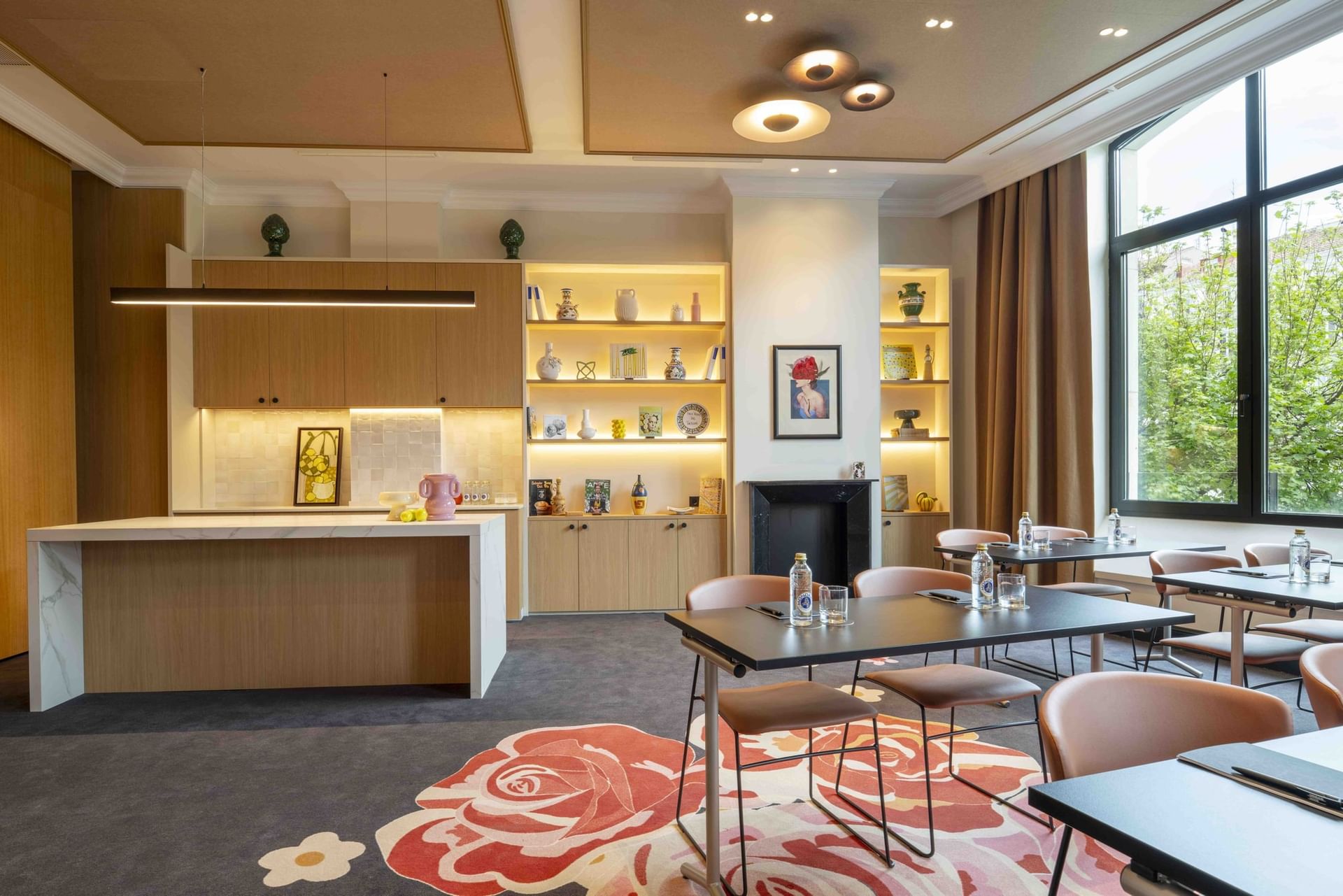 Open plan kitchen and seating area with a central island by dining tables near a window at Urban Hive Madrid