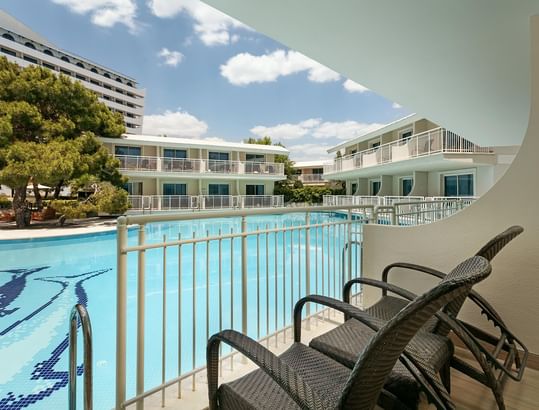 Titanic Deluxe Lara – Annex Standard Swim-Up’ta havuz manzaralı balkonda iki hasır koltuk ve zarif metal korkuluk.