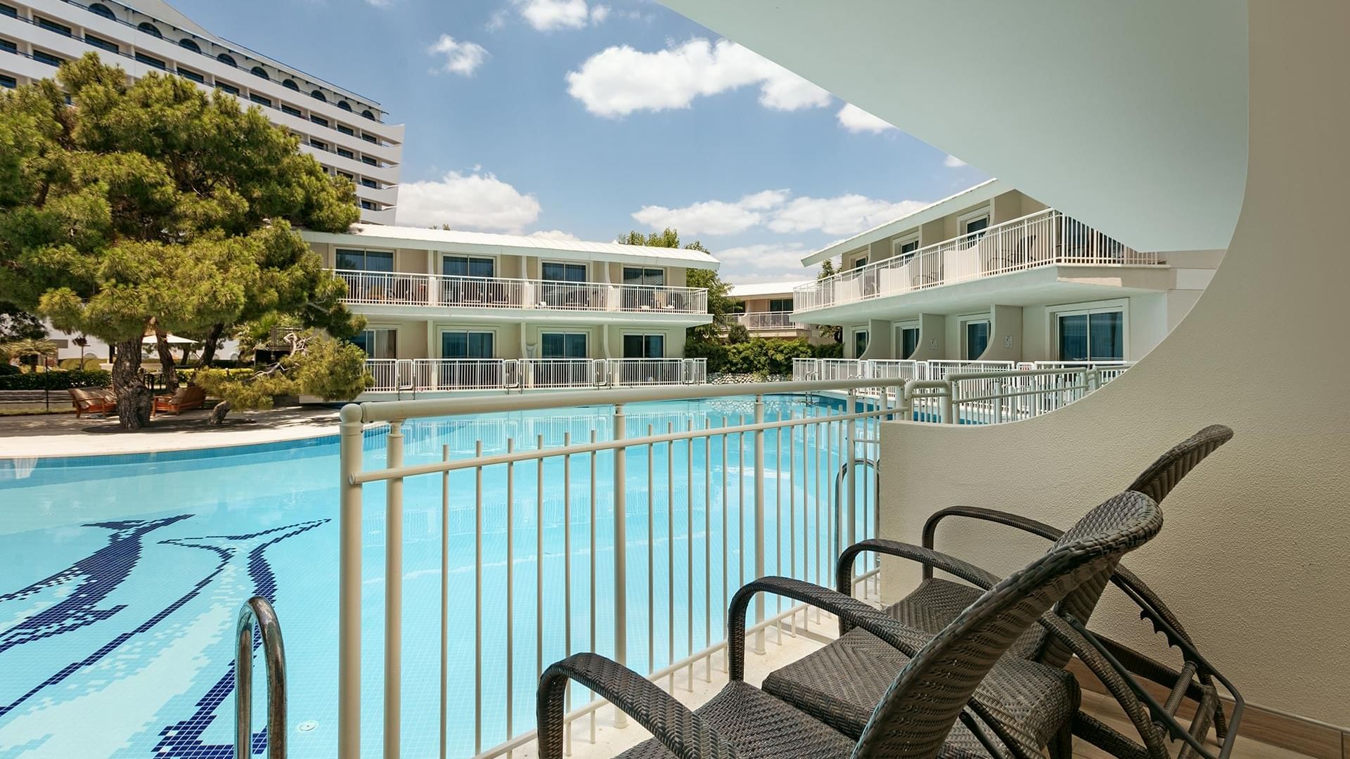 Titanic Deluxe Lara – Annex Standard Swim-Up’ta havuz manzaralı balkonda iki hasır koltuk ve zarif metal korkuluk.