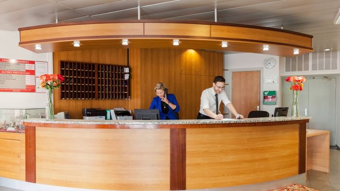 A receptionist at the reception desk in Hotel Le Forum