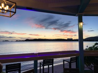 Sunset view with deck at Emerald Beach Resort, relaxing stay at a hotel in St. Thomas with balcony overlooking Caribbean Sea