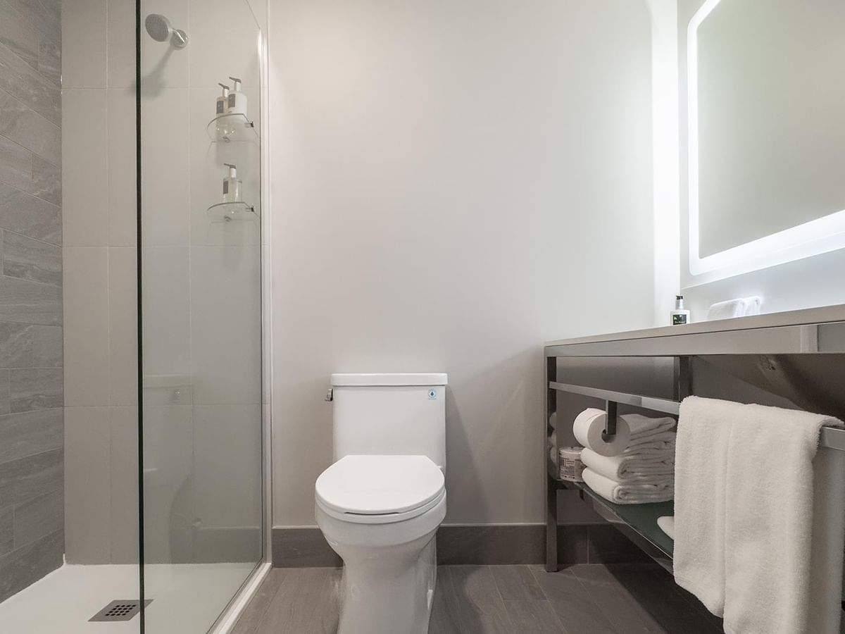 Clean and modern bathroom with white toilet, sink, and shower.