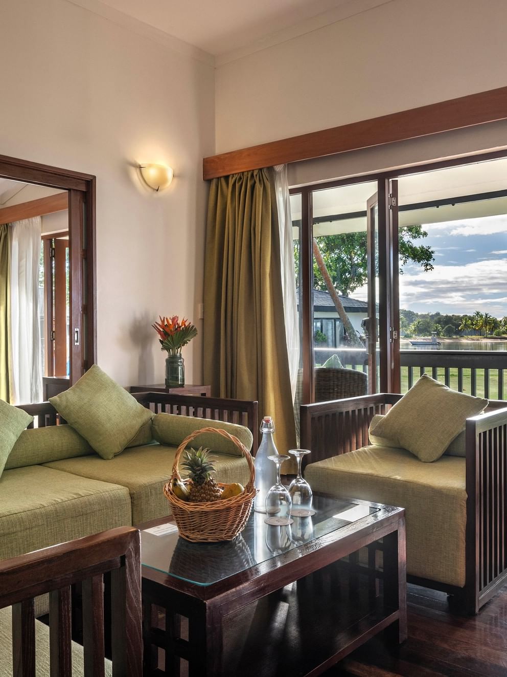 Green sofa by a coffee table under a wall sconce near a balcony in One-Bedroom Villa at The Naviti Resort - Fiji