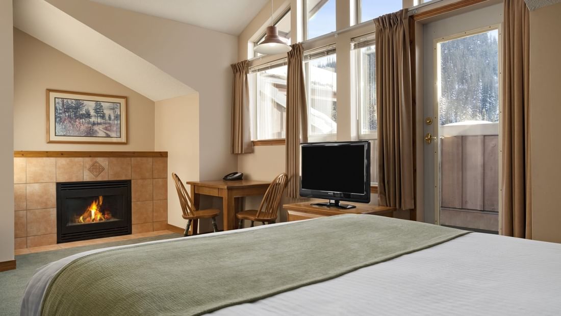 Bed in hotel room with fireplace and view of ski slopes