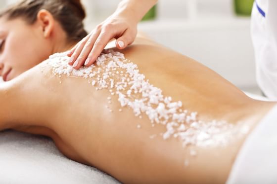 A woman having exfoliation treatment in spa at Amora Hotel