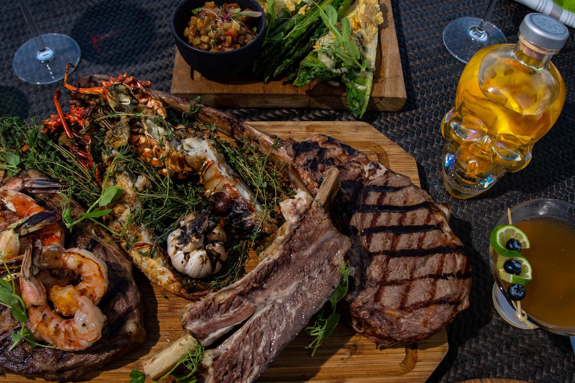 Close-up of Tomahawk steak and grilled seafood platter on a wooden board at Hacienda Del Mar Los Cabos