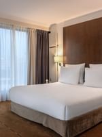 Chambre familiale avec un grand lit, un bureau et une fenêtre à l'hôtel Warwick Geneva à Genève.