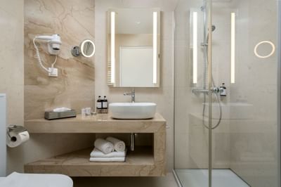 Bathroom featuring a sleek shower, minimalist vanity, round mirror, and warm lighting at Ana Hotels Europa Eforie Nord
