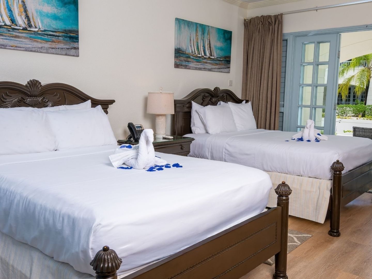 Two neatly made beds with towels and a nightstand between them at Savannah Beach Hotel.