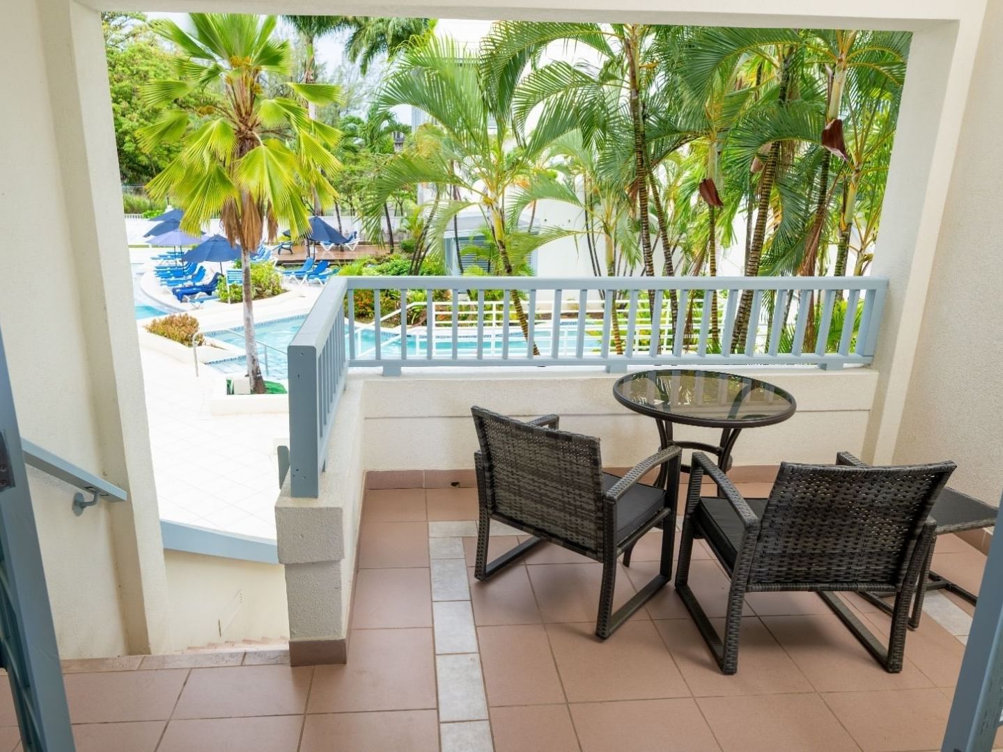 Balcony view of a pool and palm trees with patio table and chairs at Savannah Beach Hotel.