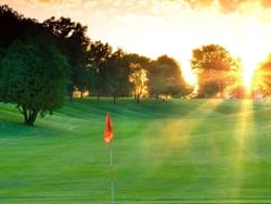 Vibrant Bellevue Golf Club bathed in golden sunlight, surrounded by lush trees near Off Shore Resort