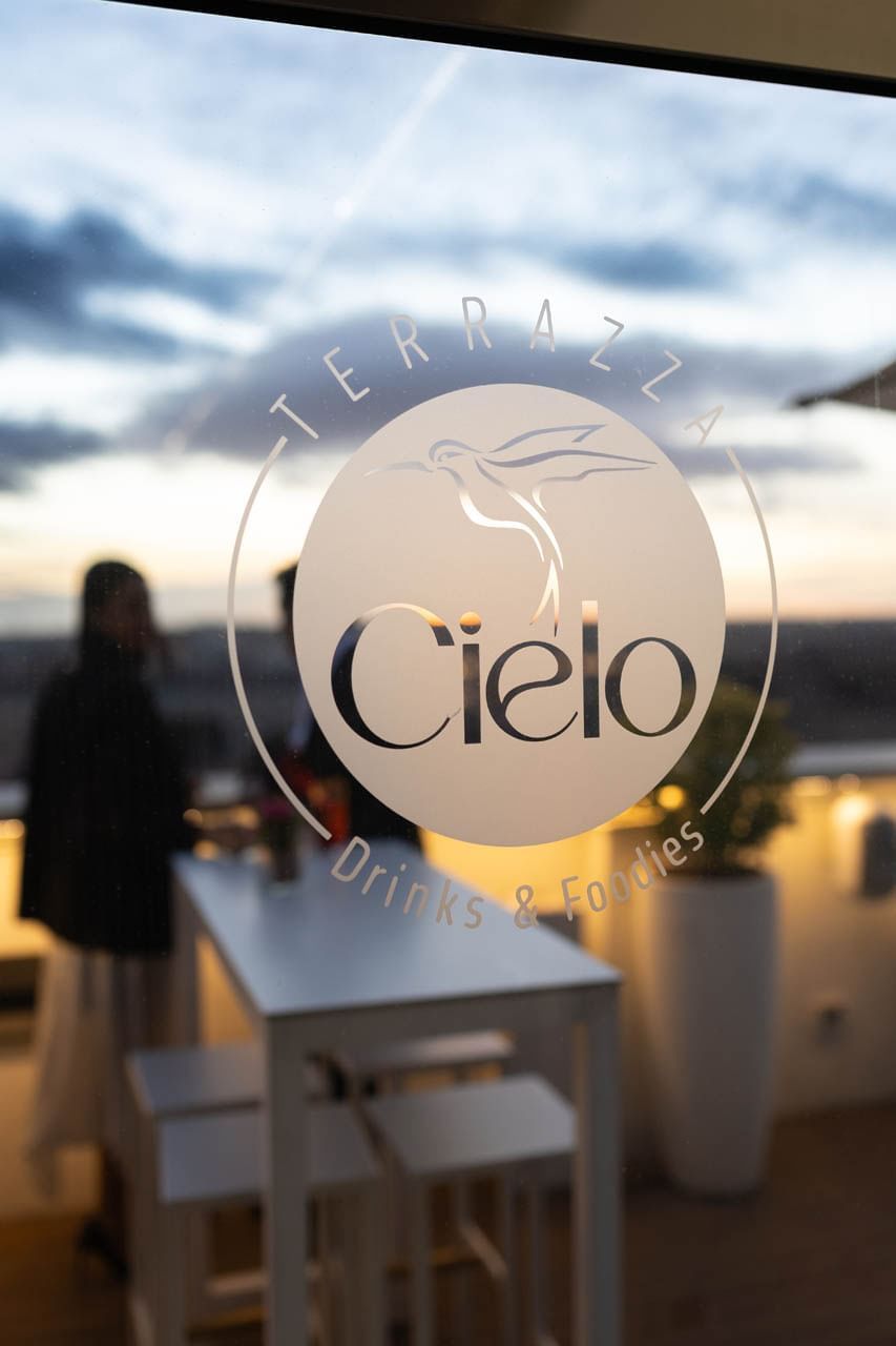 Cielo logo on a glass window with a sunset view, at Terrazza Cielo’s modern outdoor bar, The Independent