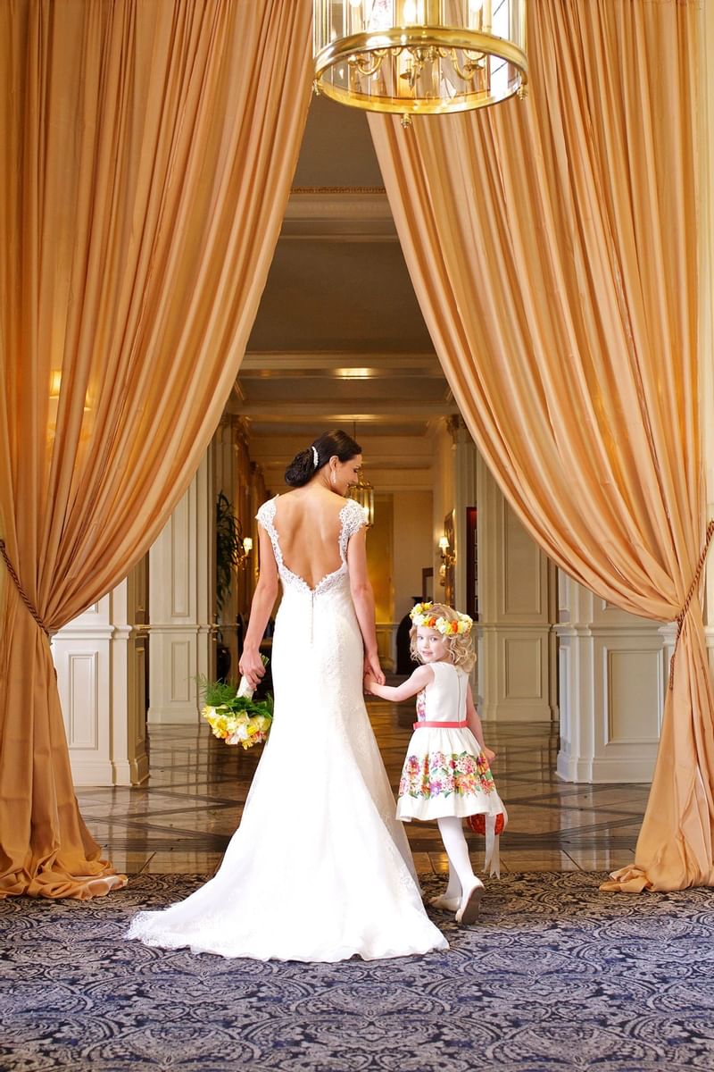 A bride holding hands with a little girl at Warwick Melrose Dallas