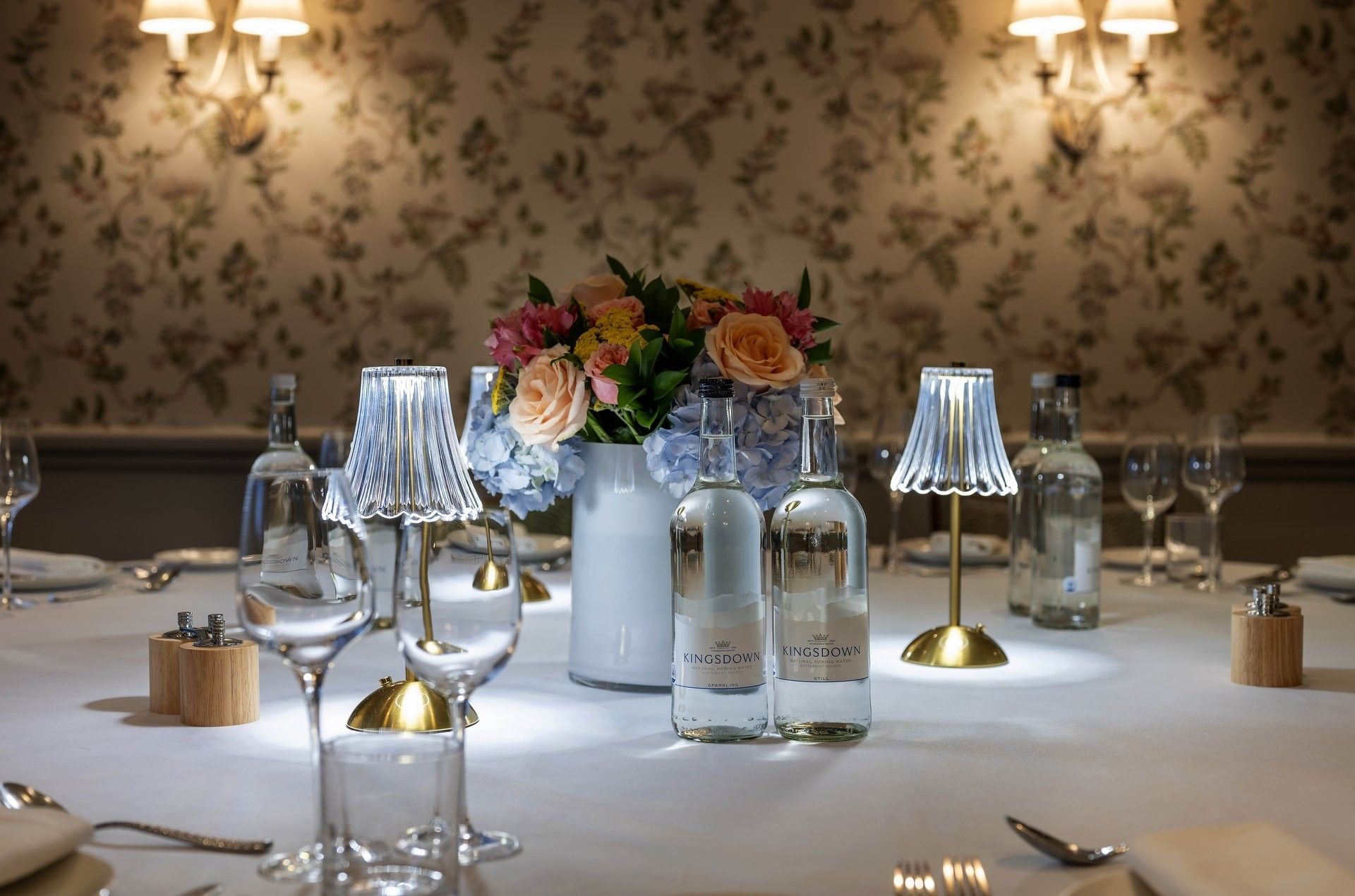 Close-up of table with water bottles & flora arrangements in The Eaton 1 at The Capital Hotel, Apartments and Townhouse