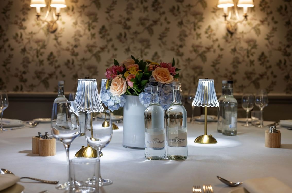 Elegant private dining room with round table, floral wallpaper, and oval mirror at The Capital Hotel, Apartments & Townhouse London Londres