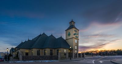 The Wildwood Hotel exterior with a clock tower and decorative green signage during the sun's dawn