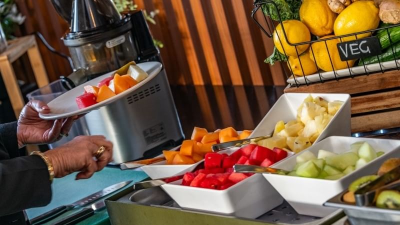 Lady grabbing food from mercure kooindah waters breakfast, fruits selection