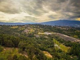 Aerial view of green rolling hills and distant mountains under a cloudy evening sky across the landscape at Casa Selvaggio
