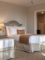 Two beds with arched headboards by wall lamps under a ceiling fan in Deluxe Double at Warwick Melrose Dallas