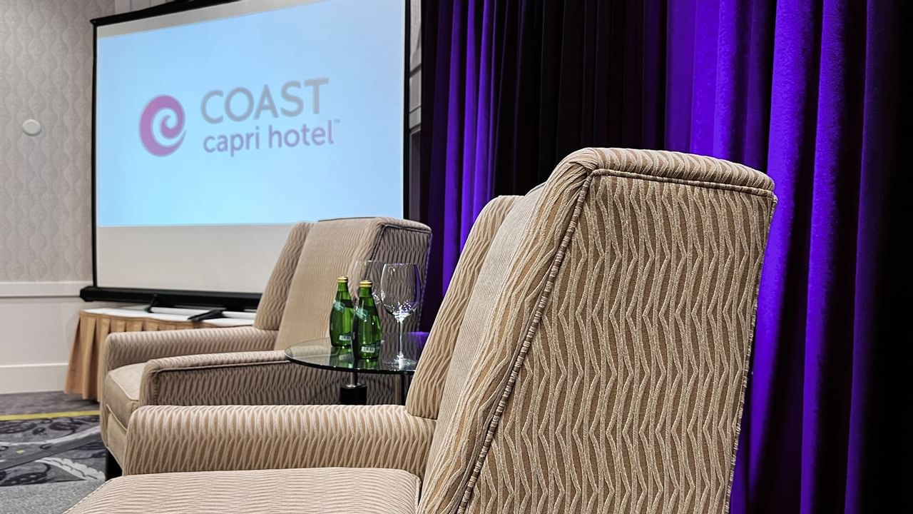 Chairs on stage with table, waters, presentation screen