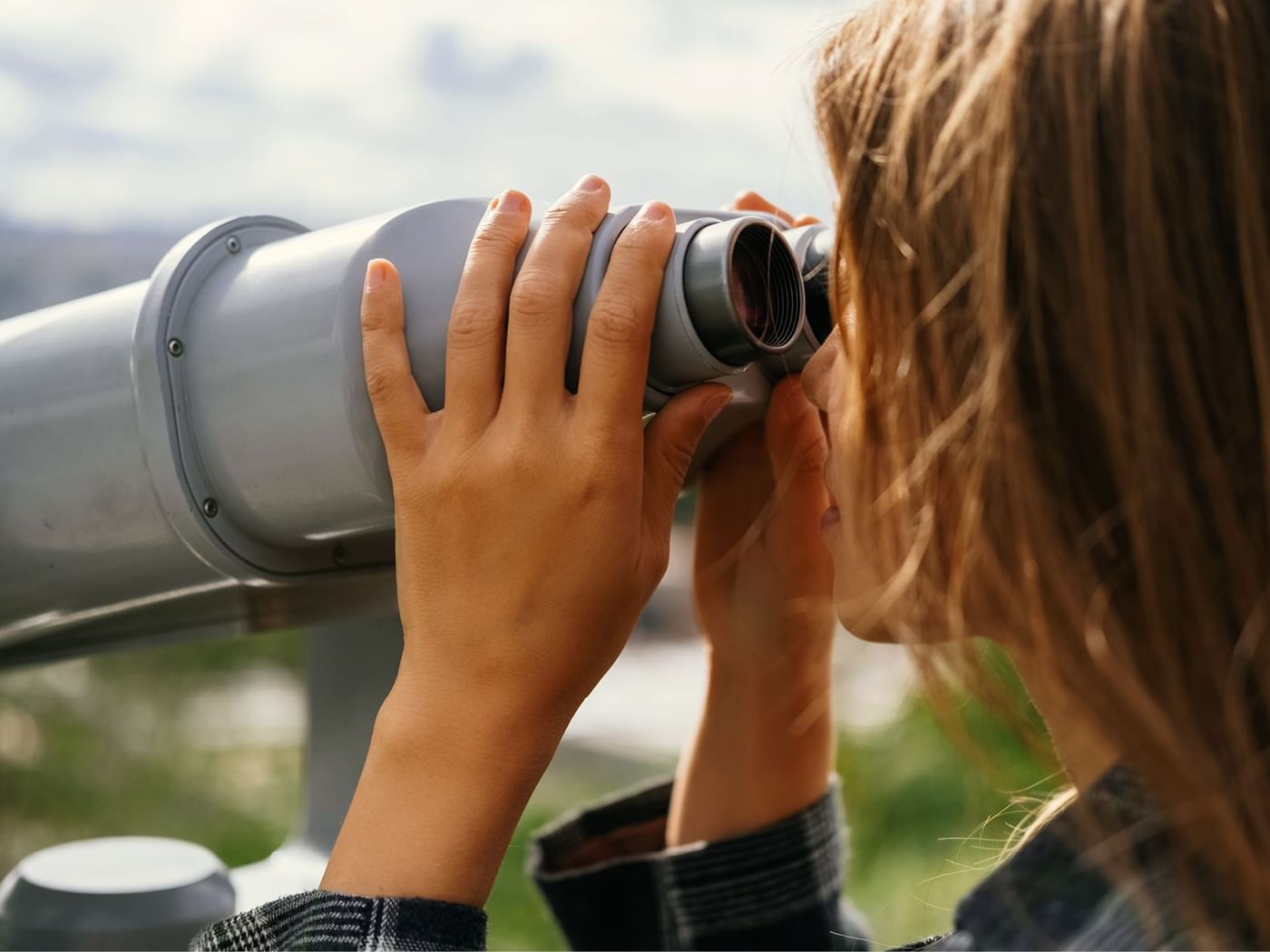 Señora contemplando la vista con un binocular cerca de los hoteles Fiesta Inn