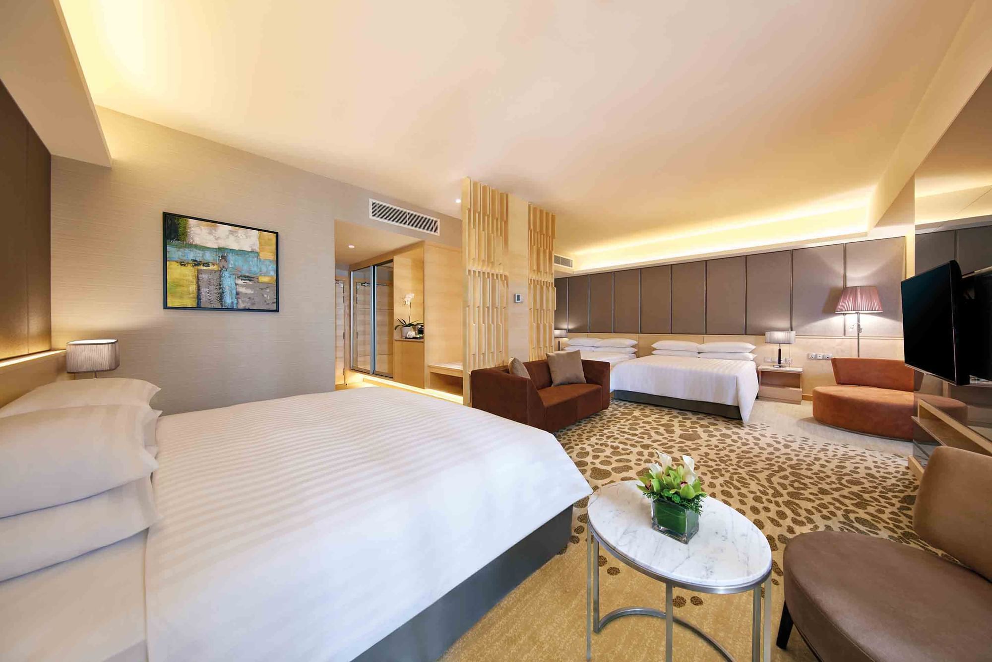 A spacious modern room with three beds, a sofa & elegant decor at Sunway Hotels & Resorts