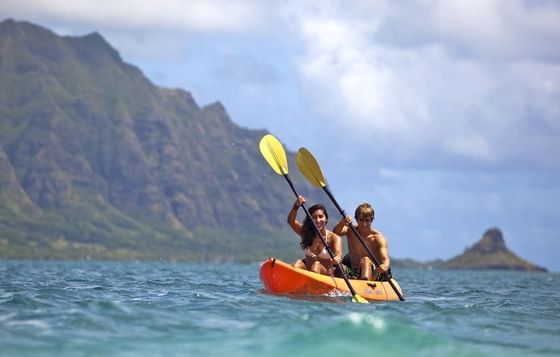 Couple kayaking on a sunny day in the sea near Paradise Bay Resort