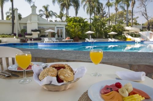 Primer plano del desayuno en una mesa junto a la piscina de Gamma Hotels