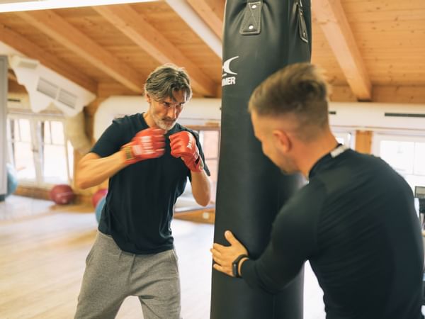 A man with a trainer hitting a punching bag at Liebes Rot