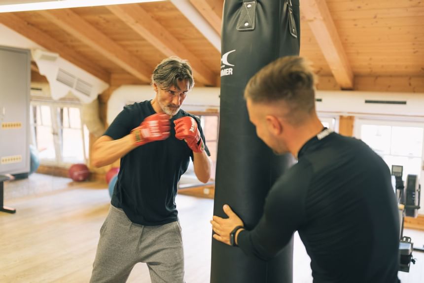 A man with a trainer hitting a punching bag at Liebes Rot