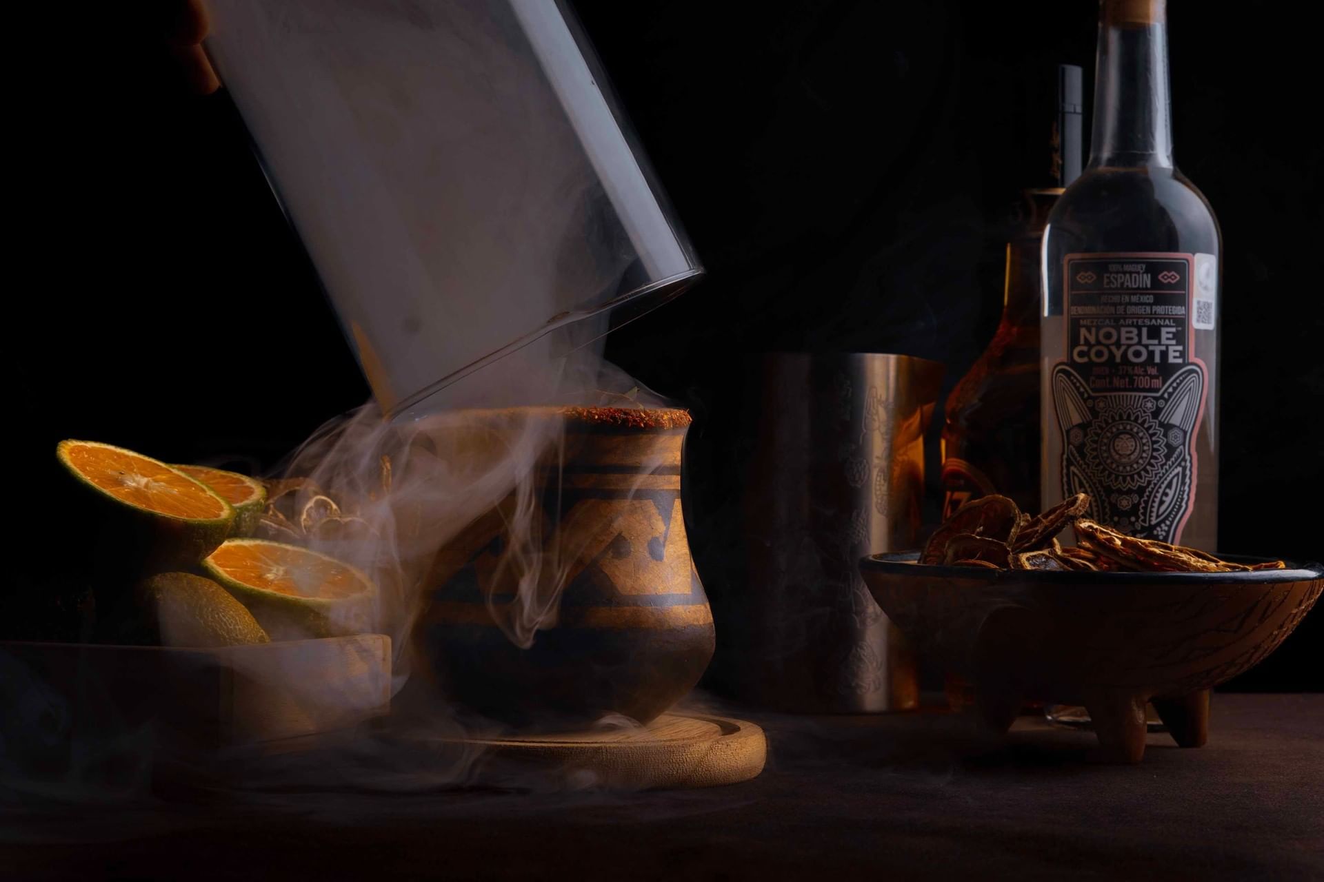 An artisanal smoky cocktail featuring citrus garnishes and mezcal spirits served at Cala Luna Boutique Hotel