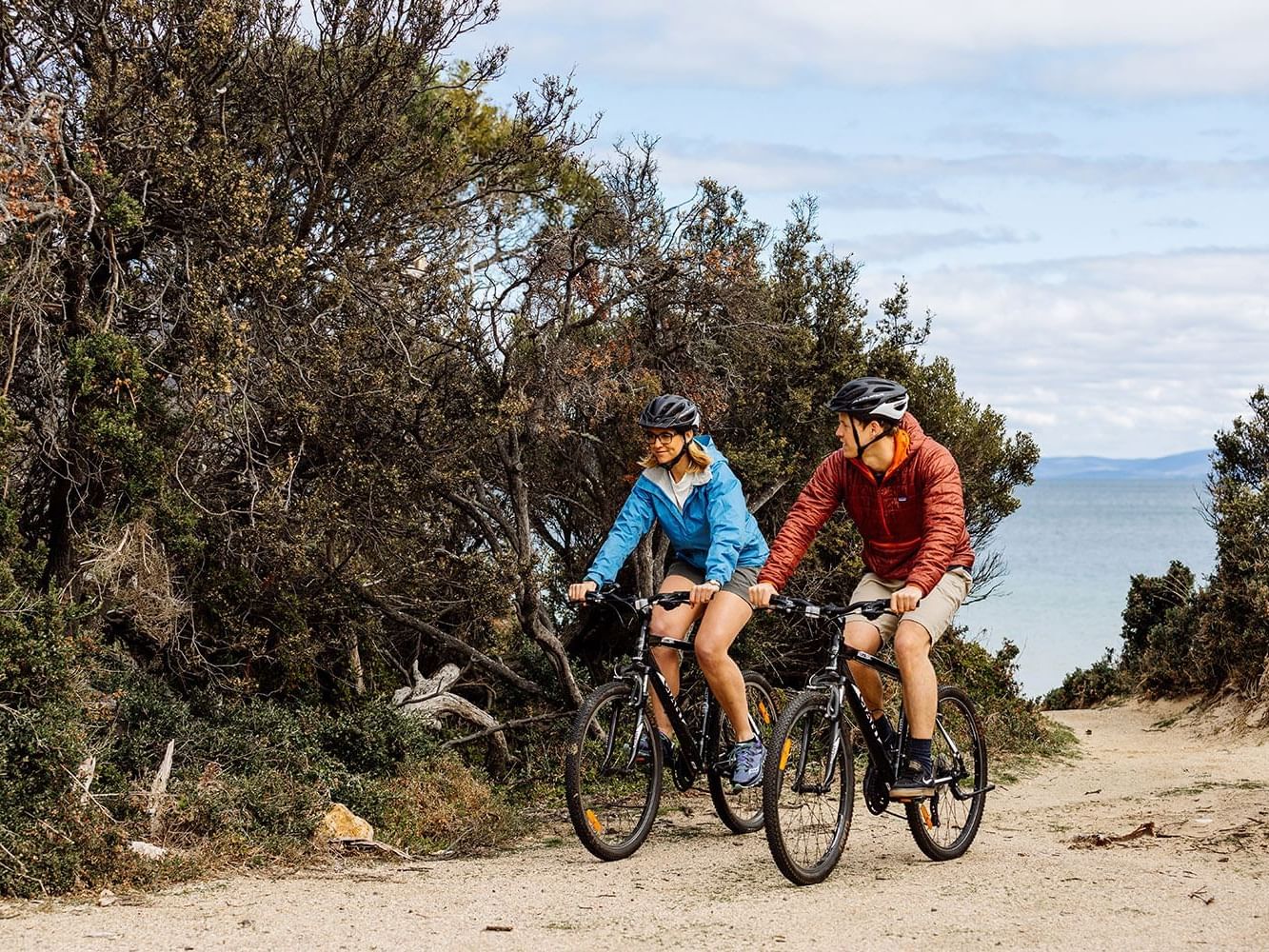 Couple riding bikes on a trail near Freycinet Lodge