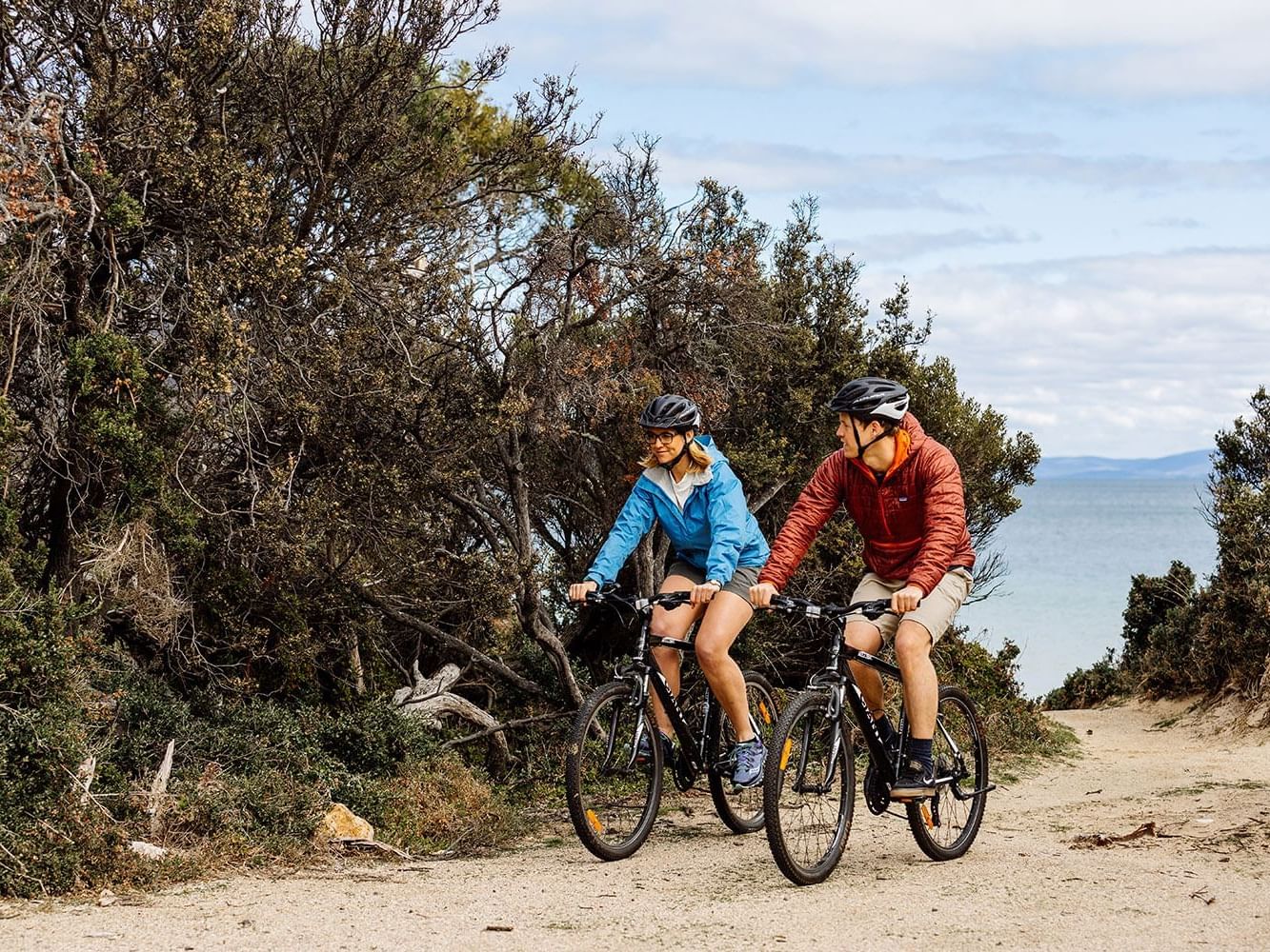 Couple riding bikes on a trail at Freycinet Lodge